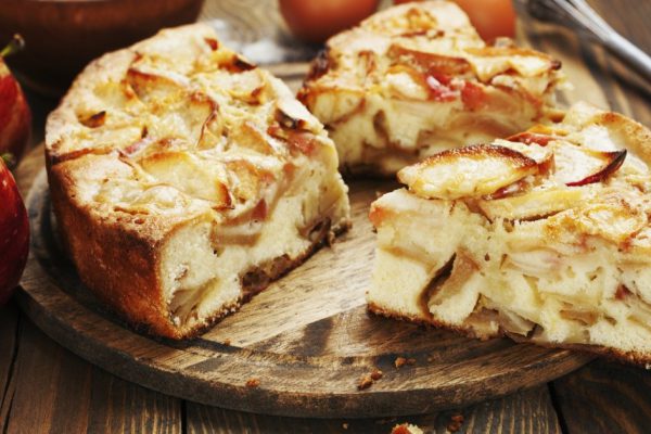Apple pie and red apples on a wooden table