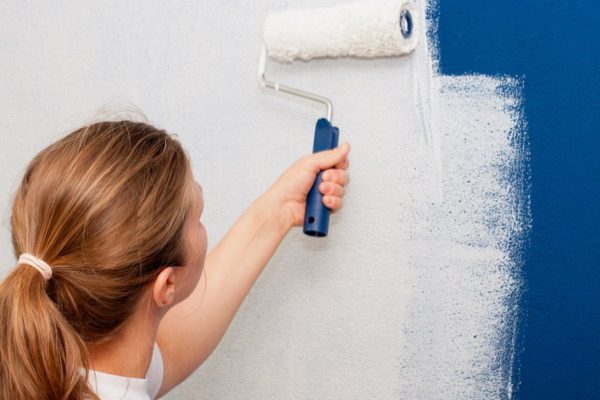 Woman painting interior wall of house with a roller