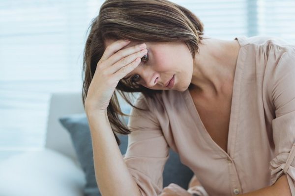 Sad young woman sitting on sofa at home