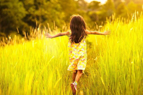 Little girl running on meadow with sunset