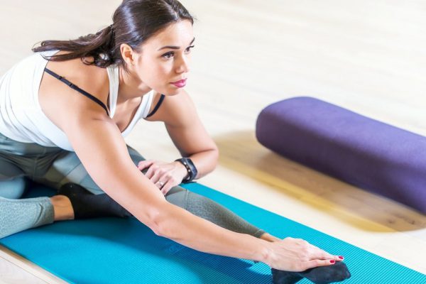 Fit woman doing stretching pilates exercises in fitness studio