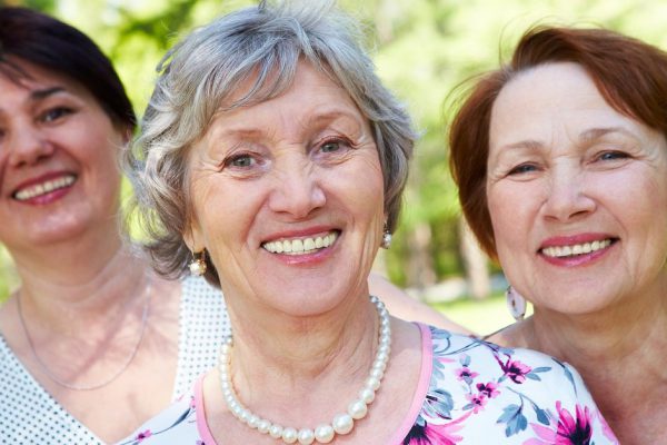 Portrait of three aged women looking at camera with smiles