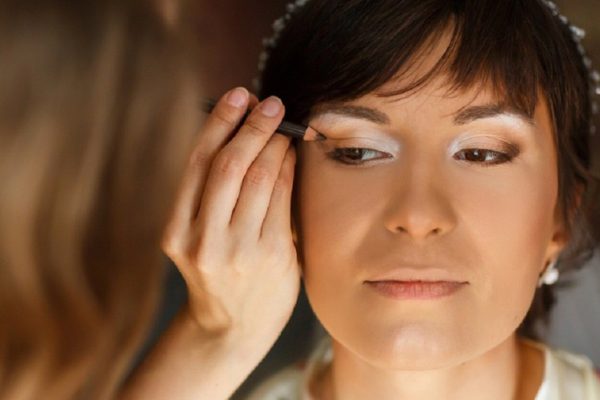visagiste doing makeup grown beautiful bride in the room