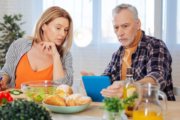 Feeling unsatisfied. Couple of businessmen feeling unsatisfied with morning news during breakfast