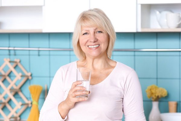 Beautiful mature woman drinking water in kitchen