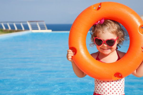 little girl in swimsuit takes lifebuoys backgraund swimming pool