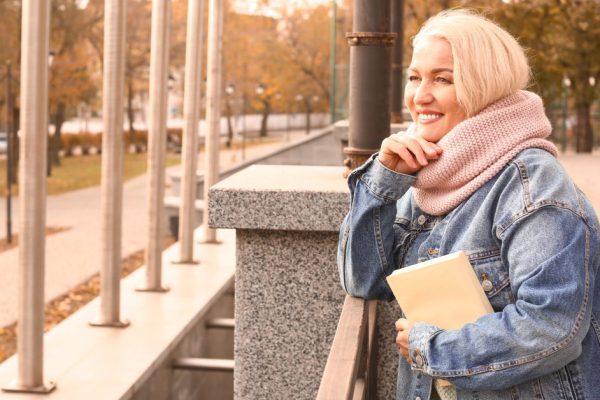 Portrait of beautiful mature woman with book in autumn park