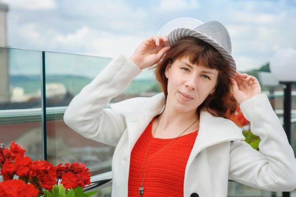 beautiful woman in a white coat near the red flowers in the background Lviv.