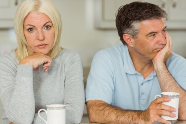 Mature couple having coffee together not talking at home in the kitchen