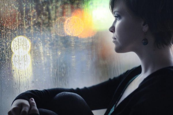 sad girl on the windowsill looking out the window