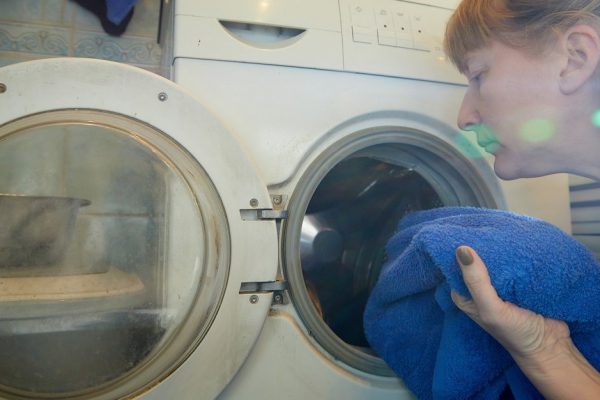 Housewife looking into the washing machine in the bath room. The concept of homework and Laundry at home