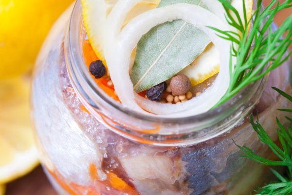 Marinated herring in a jar with vegetables and herbs
