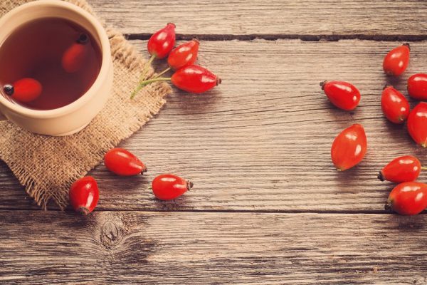 cup of tea with hip roses, on wooden table