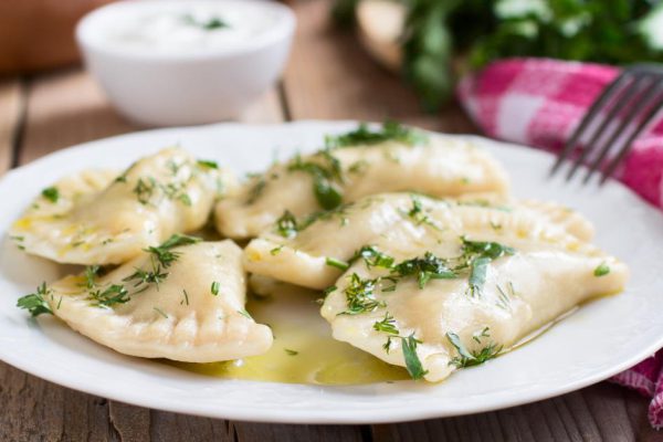 Traditional dish of Slavic cuisine. Varenyky on a white plate on wooden table