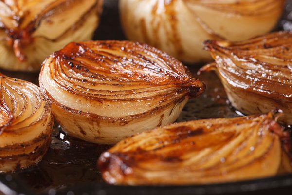 сaramelized onion halves with balsamic vinegar in a pan close-up, horizontal
