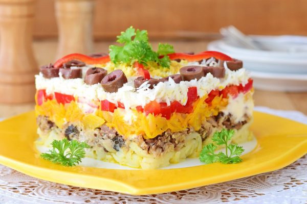 Traditional Russian layered salad Mimosa composed of canned fish covered with layers of boiled potato, carrot, onion, cheese, eggs and mayonnaise.