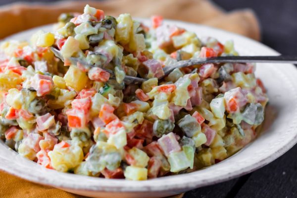 Olivier salad with mayonnaise on dark wood, new year