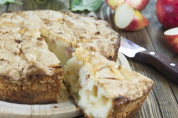 Apple pie and red apples on a wooden table