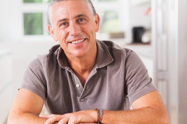 Happy man sitting at table in kitchen