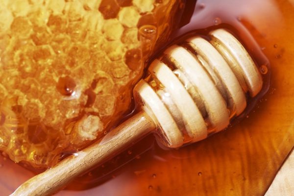 Honeycomb with Wooden Dipper on Wooden Plate Closeup