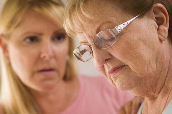 Young Adult Woman Consoles Sad Senior Adult Female.
