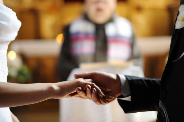 Bride and groom are holding each other's hands during church wedding ceremony