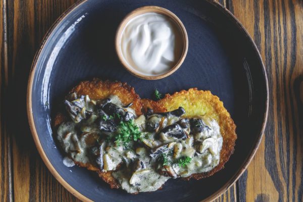 National Belarusian dish of draniki (pancake) with mushrooms under sauce and kvass. view from above