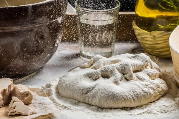Sprinkling flour on fresh pizza dough
