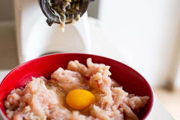 Electric meat grinder and a plate of meat with egg. Ingredients for the preparation of cutlets.