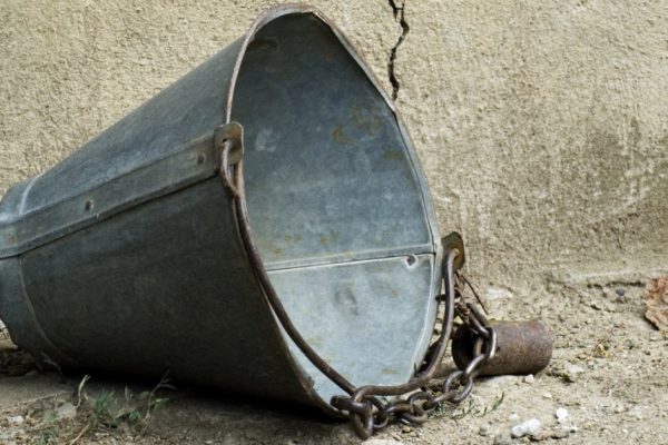 Old broken scutlle in front of cracked wall of well
