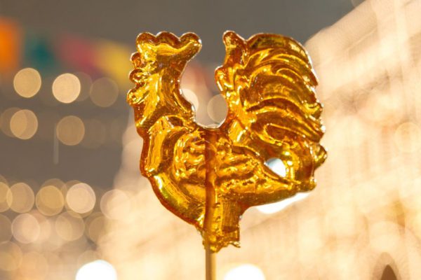 Cockerel candy on a stick. Hard candy rooster. Rooster candy symbol.