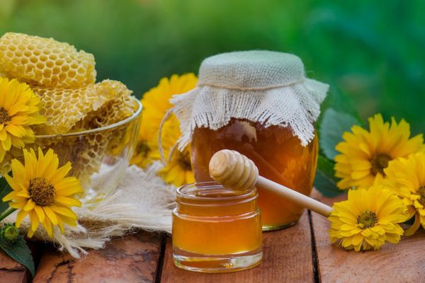 Honey jar and honeycomb on wooden table. Honey jar and flowes on table  on abstract blurry bokeh background