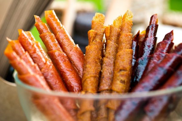 Colorful fruit leather rolls in glass bowl, selective focus.