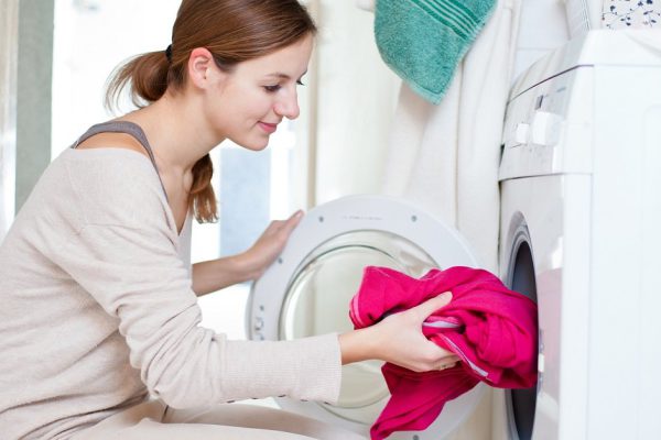 Housework: young woman doing laundry (shallow DOF; color toned image)
