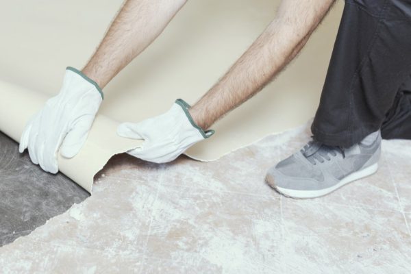 Professional contractor removing an old linoleum flooring: home renovation concept