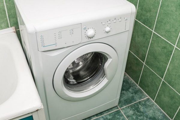 The photo of the light white bathroom with household appliances