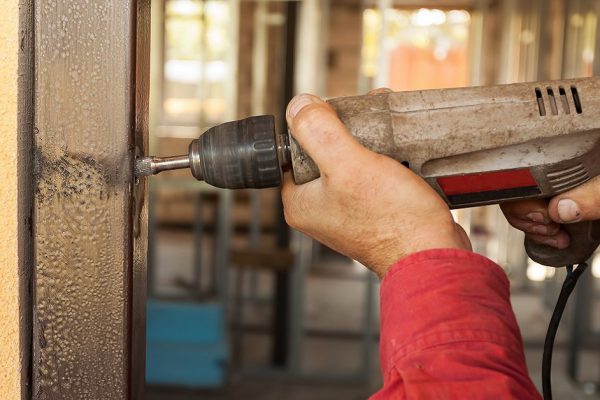Carpenter at door installation with electric drill