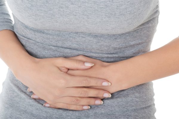 Young casual girl woman is having stomach ache. Over white background.