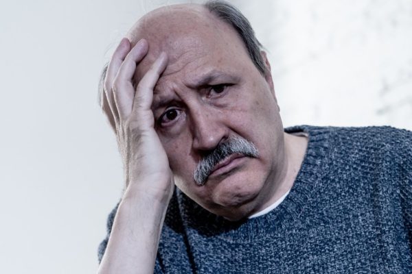 Overwhelmed old senior man suffering alone at home feeling confused sad alone on couch at home in Aging Retirement widower Dementia and Alzheimer concept.