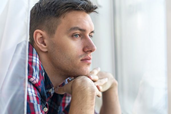 Handsome pensive man guy watching through the window concept sadness sorrow pain waiting.