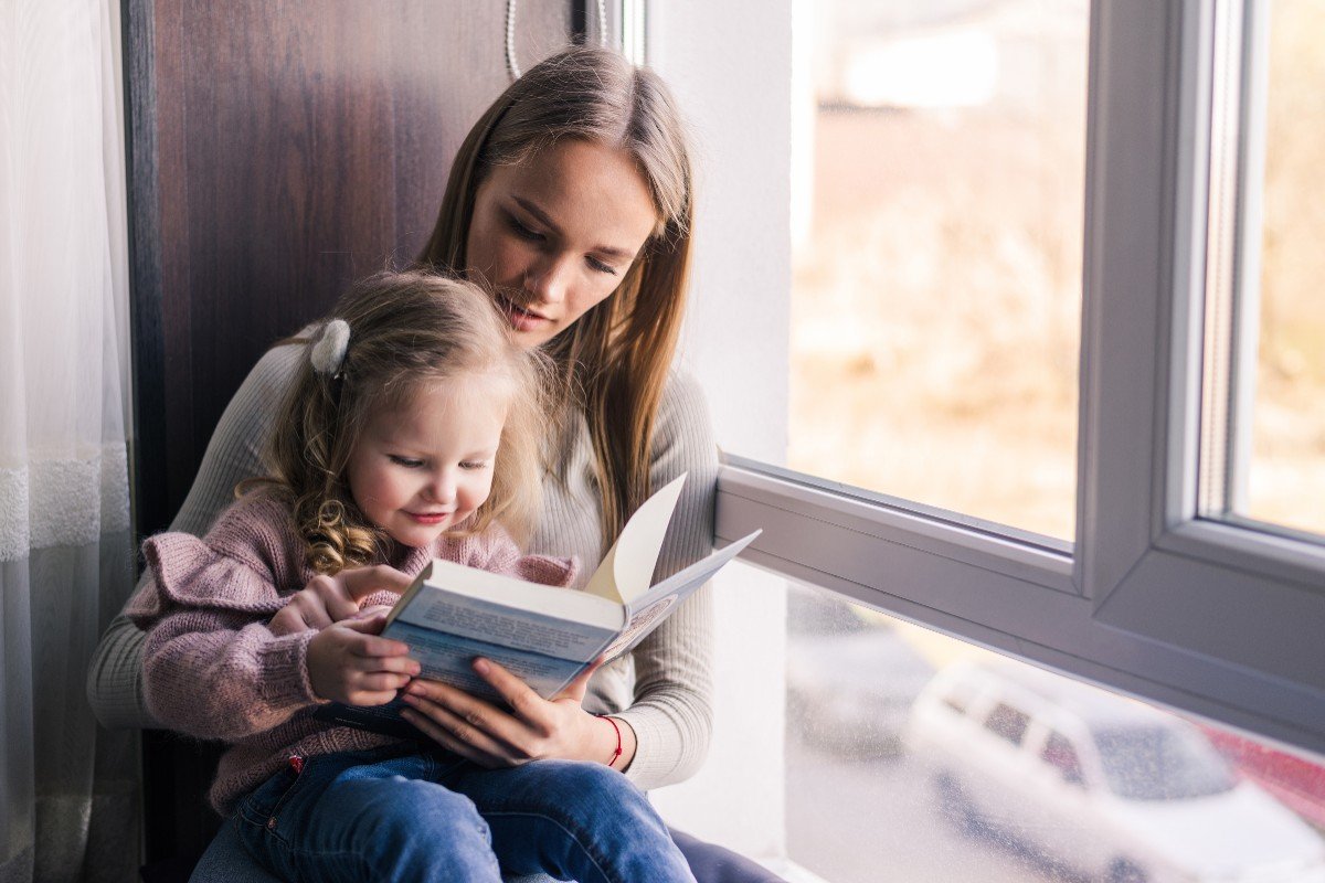 Родители далеко живет. Няня читает книгу ребенку. Reading book to little daughter,. Ребенок сидит с книгой с открытыми глазами фото. Ребенок и няня фото деревня.