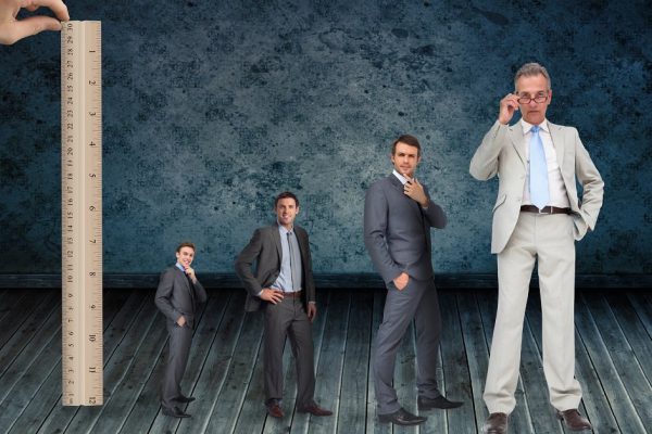 Composite image of hand measuring stages of businessmans life with ruler against dark grimy room