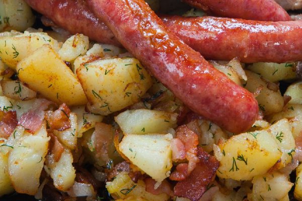 grilled sausages with potatoes, and roasted meat on a grill pan.