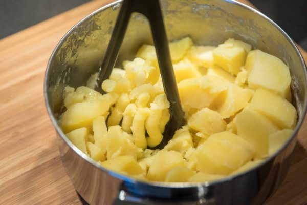 Mashed potatoes preparation in the pot on wooden background