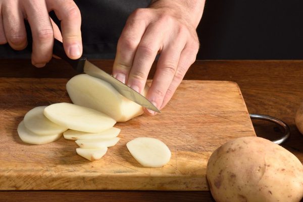detallle of a chef slicing potatoes