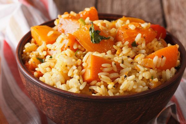 Vegetarian food: rice with pumpkin in a bowl on the table. Horizontal