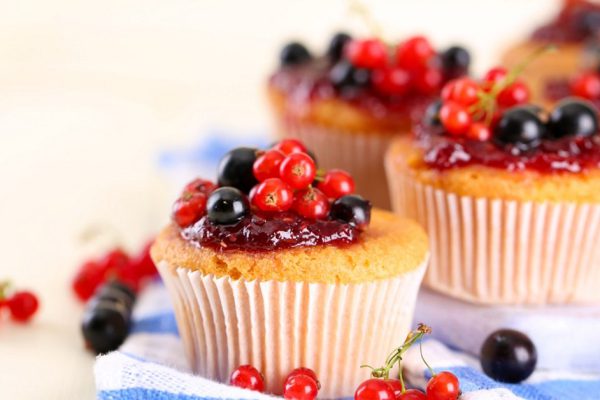 Tasty muffins with berries on white wooden table
