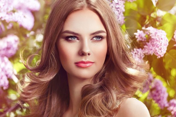 Beautiful Woman with Flowers of Lilac. Spring Blossom. Sexy Glamour Summer Beautiful Lady with Healthy and Beauty Hair