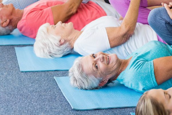 Instructor performing yoga with seniors during sports class