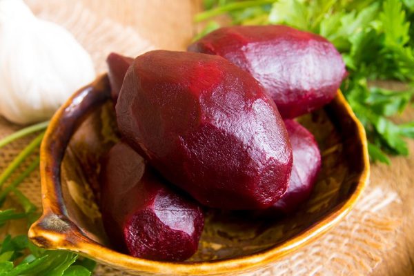 Boiled beetroots in bowl with parsley over rustic wooden table. Ingredient of traditional russian cuisine.